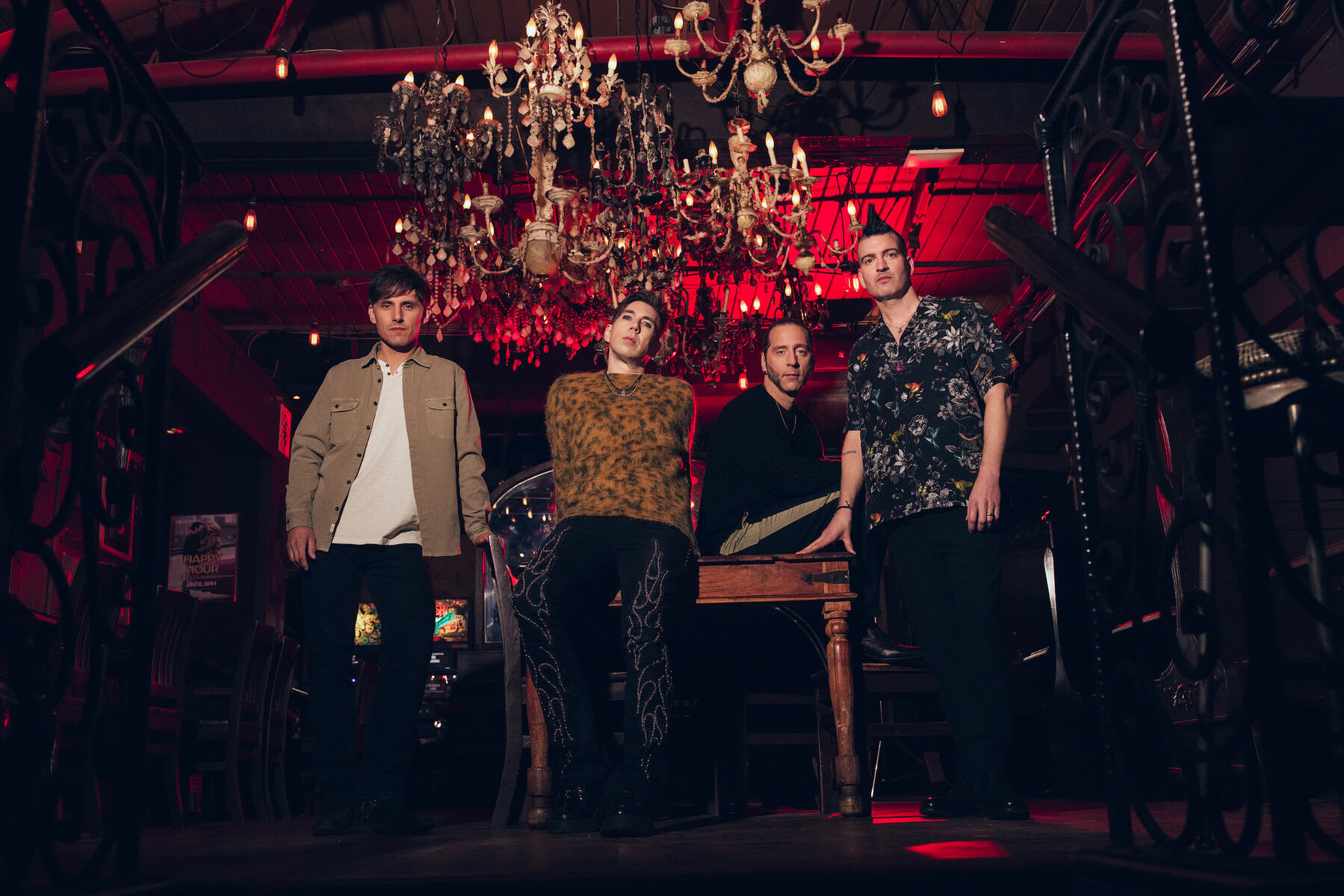 A band performing live on stage with dramatic red lighting, vintage chandeliers, and ornate decor creating an intense and stylish atmosphere.